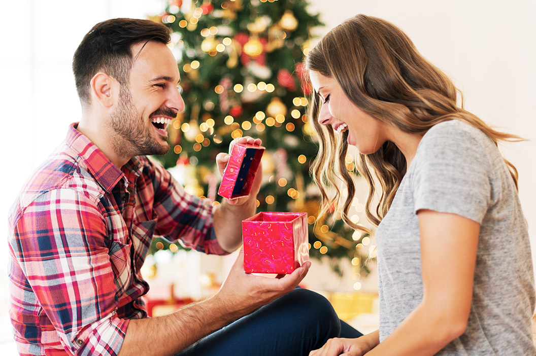 couple opening gifts in front of christmas tree